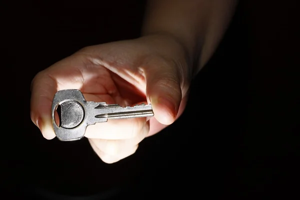 Ręka trzyma klucz między kciukiem i palcem wskazującym — Zdjęcie stockowe