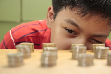 Boy Looking At a Stack of Coins clipart