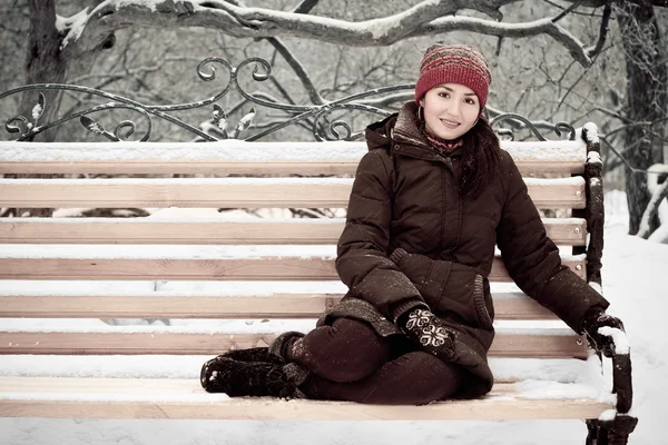 Mujer joven en el parque de invierno en un banco —  Fotos de Stock