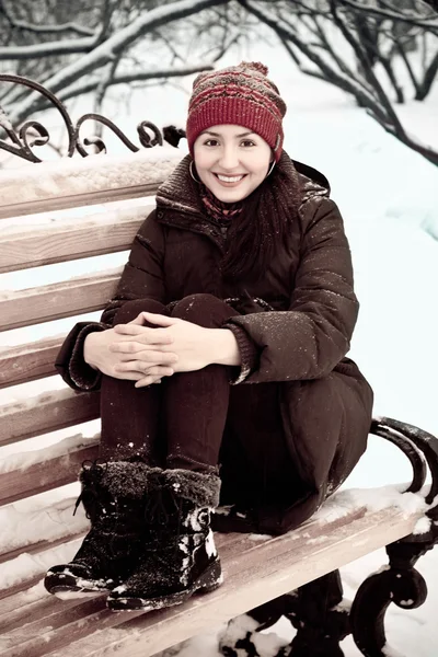 Mujer joven en el parque de invierno en un banco —  Fotos de Stock