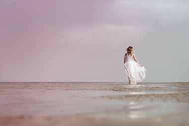 Woman walking on the sea shore clipart