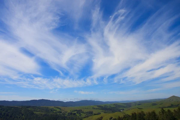 Zachmurzone niebo niebieskie i zielone wzgórza — Zdjęcie stockowe