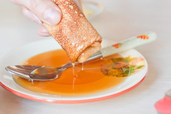 Arm hält Pfannkuchen mit Honig — Stockfoto