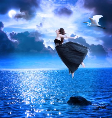 Beautiful girl jumping into the blue night sky clipart