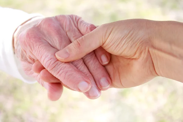 Jeune tenant la main d'une dame âgée — Photo