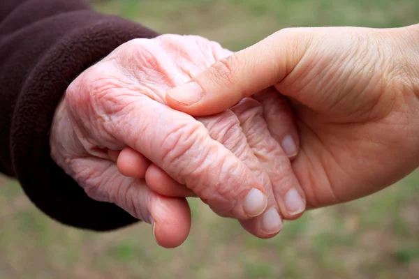 Senior et jeune tenant la main — Photo
