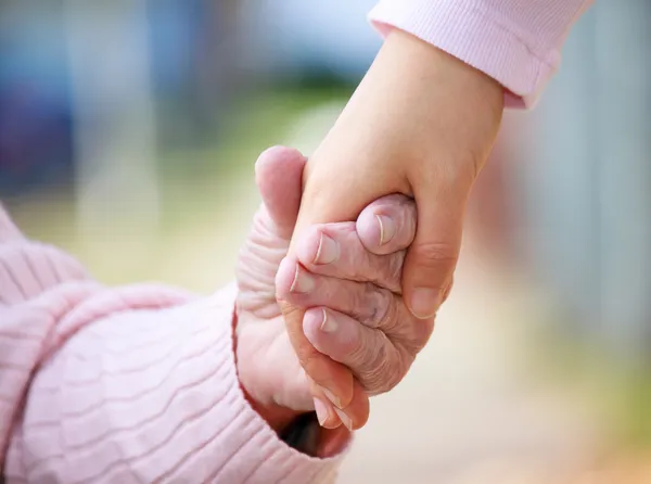 Högre och unga hålla händer — Stockfoto