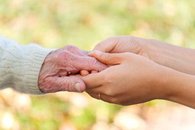 Senior and young holding hands clipart