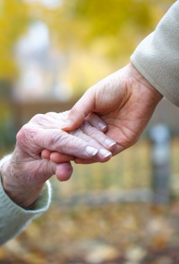 Senior and young holding hands clipart