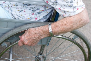 Senior's hand on wheel of wheelchair clipart