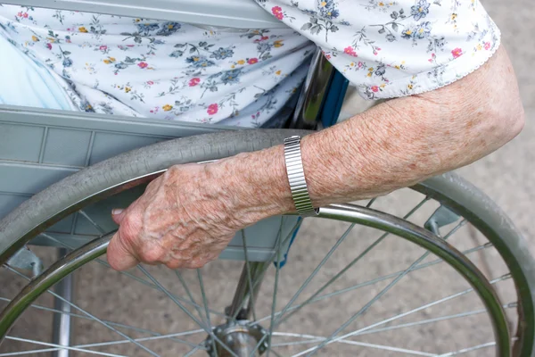 Mano de senior sobre rueda de silla de ruedas —  Fotos de Stock