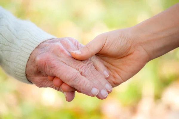 Senioren en jongeren hand in hand — Stockfoto