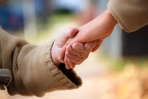 Senior and young holding hands — Stock Photo, Image