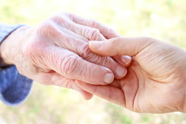 Senioren en jongeren hand in hand — Stockfoto