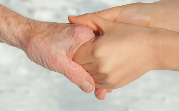 Senioren en jongeren hand in hand — Stockfoto