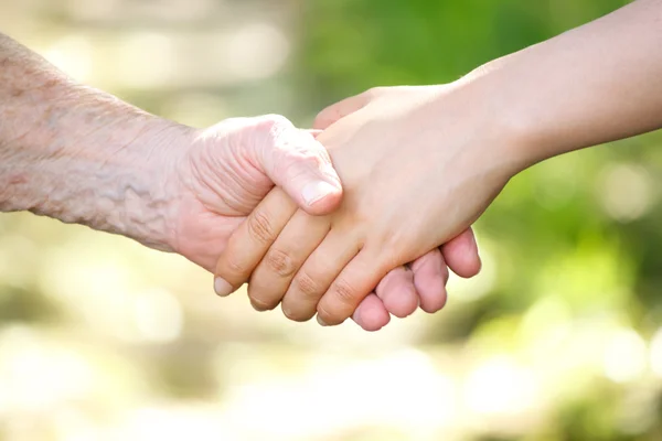 Äldre och unga kvinnor hålla hand — Stockfoto
