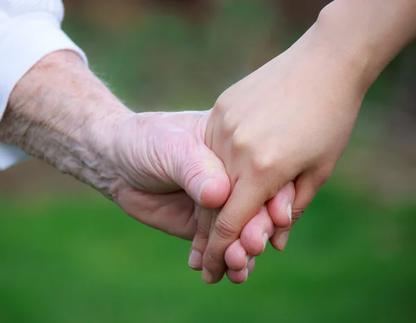 Jovem segurando a mão do idoso — Fotografia de Stock