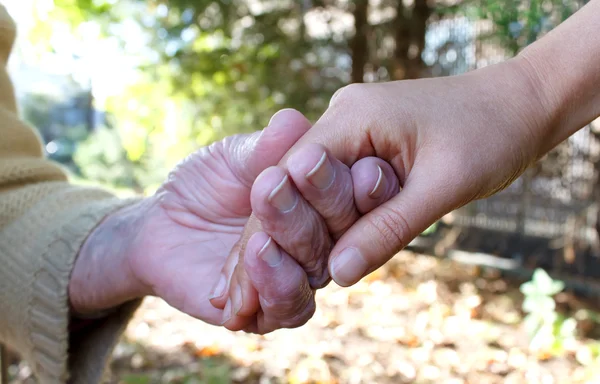 Young and senior holding hands — Stock Photo, Image