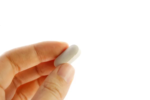 Mão segurando uma pílula branca — Fotografia de Stock
