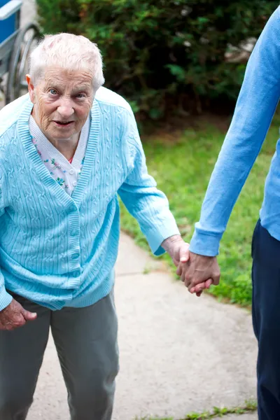 Señora mayor caminando con el cuidador — Foto de Stock