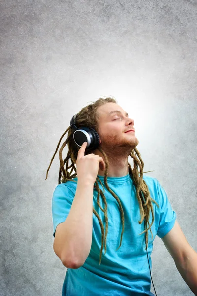 Retrato de um jovem com cadeados ouvindo música em fones de ouvido — Fotografia de Stock