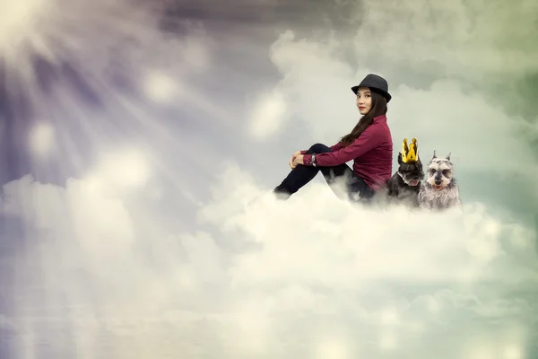 Young woman sitting on the cloud with dogs — Stock Photo, Image