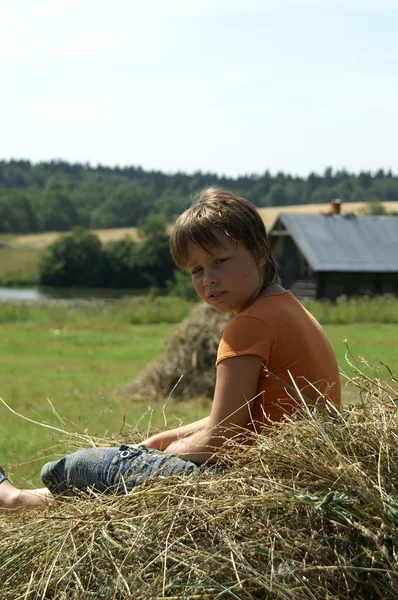 The boy sits on a haystack in a half-turn — Stock Photo, Image