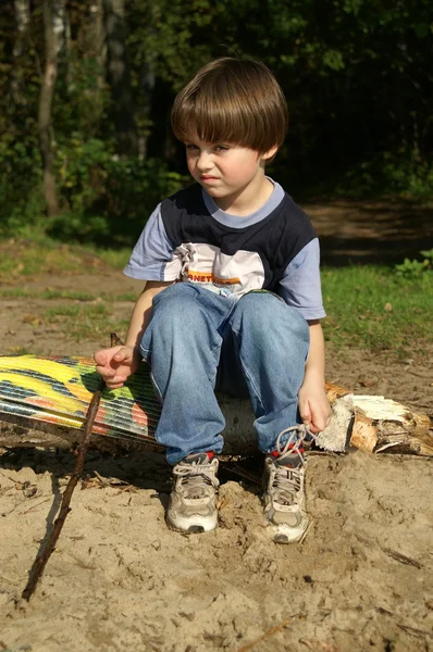 The harmful boy sits on a sandy beach — Stock Photo, Image
