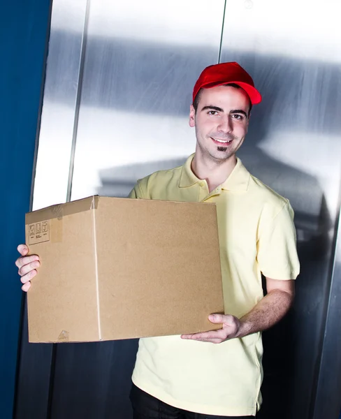 Young handsome smiling delivery man with box — Stock Photo, Image