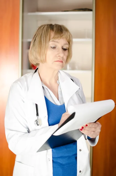 Média idade mulher médico tomar notas — Fotografia de Stock