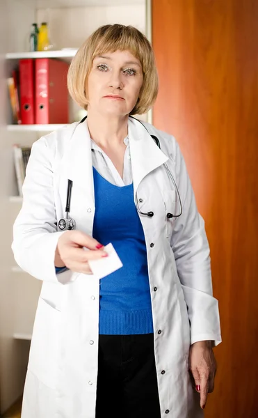 Mature doctor woman giving business card — Stock Photo, Image