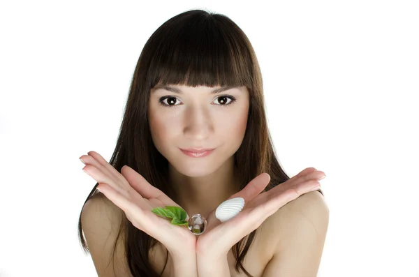 Beautiful girl in spa holding near her face fresh green leaf and shell — Stock Photo, Image