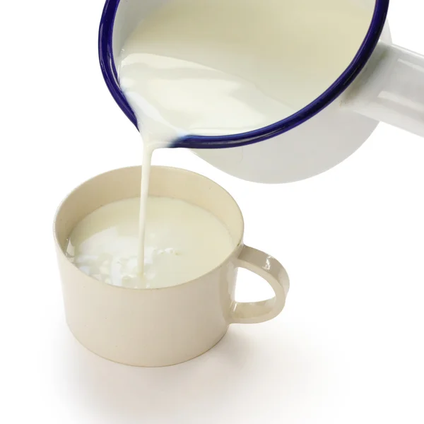 Pouring milk into a cup by an enamel milk pot — Stock Photo, Image