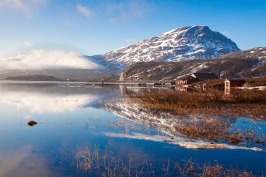 Winter mountain and lake reflection on sunny day with blue skies clipart