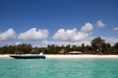 Beach restaurant on beautiful tropical beach with moored boat clipart