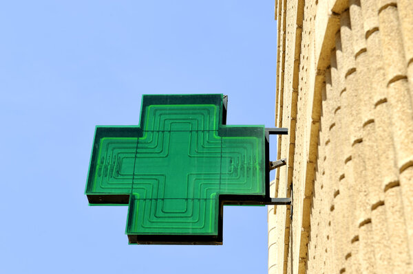 Green sign at pharmacy against clear blue sky