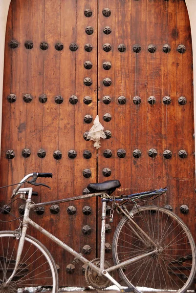 Bike parked against old door — Stock Photo, Image