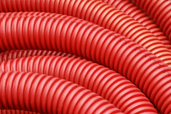 Катушка из красной пластиковой гофрированной водопроводной трубы крупным планом — стоковое фото