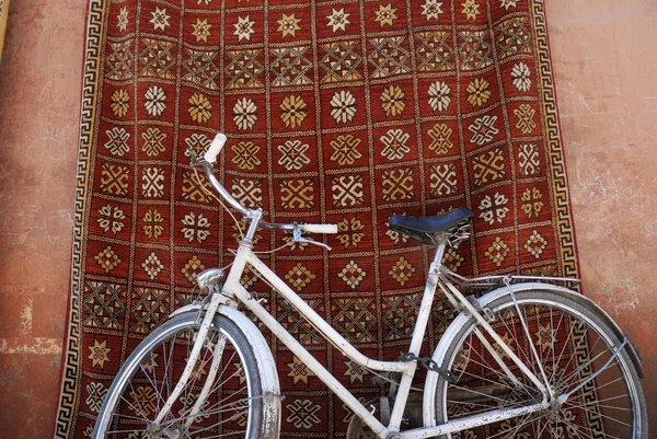Bicicleta branca na frente de um tapete tradicional em Marraquexe, Marrocos — Fotografia de Stock