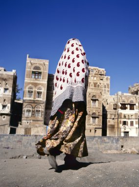 Veiled Muslim woman walks on Sana’a street, Yemen clipart