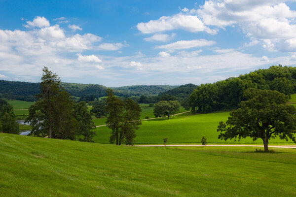 This is a photo of a country landscape with rolling hills and a blue sky with clouds.