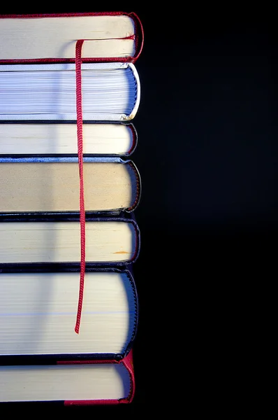 stock image Stack of Books in a tower with a red bookmark in a black backgro