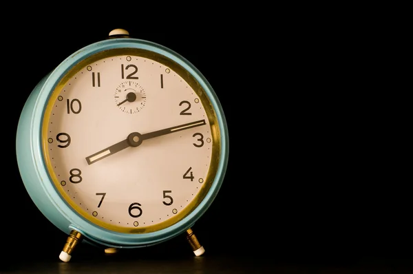 Old alarm clock showing twelve past eight on black background. — Stock Photo, Image