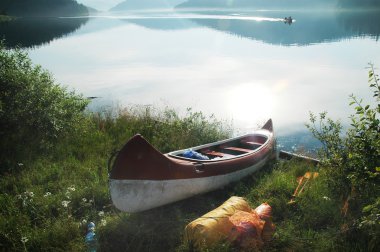 Canoe near the lake in morning lights clipart