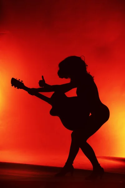 Mulher com silhueta de guitarra em fundo vermelho — Fotografia de Stock