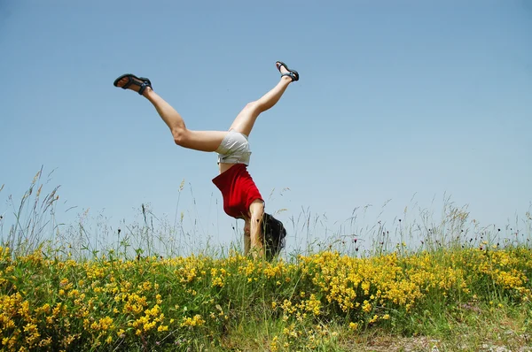 Young woman doing a cartwheel in a meadow — Stock Photo, Image