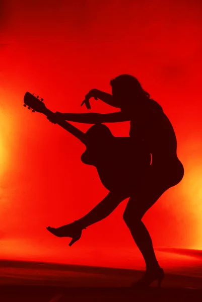 Mulher com silhueta de guitarra em fundo vermelho — Fotografia de Stock