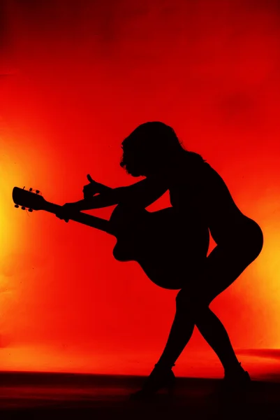 Žena s kytara silueta na červeném pozadí — Stock fotografie