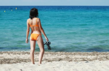 Turuncu bikini floplar kıyı üzerinde tutan kadın