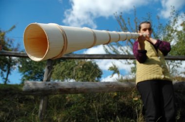 Old woman playing the traditional Romanian alpenhorn clipart